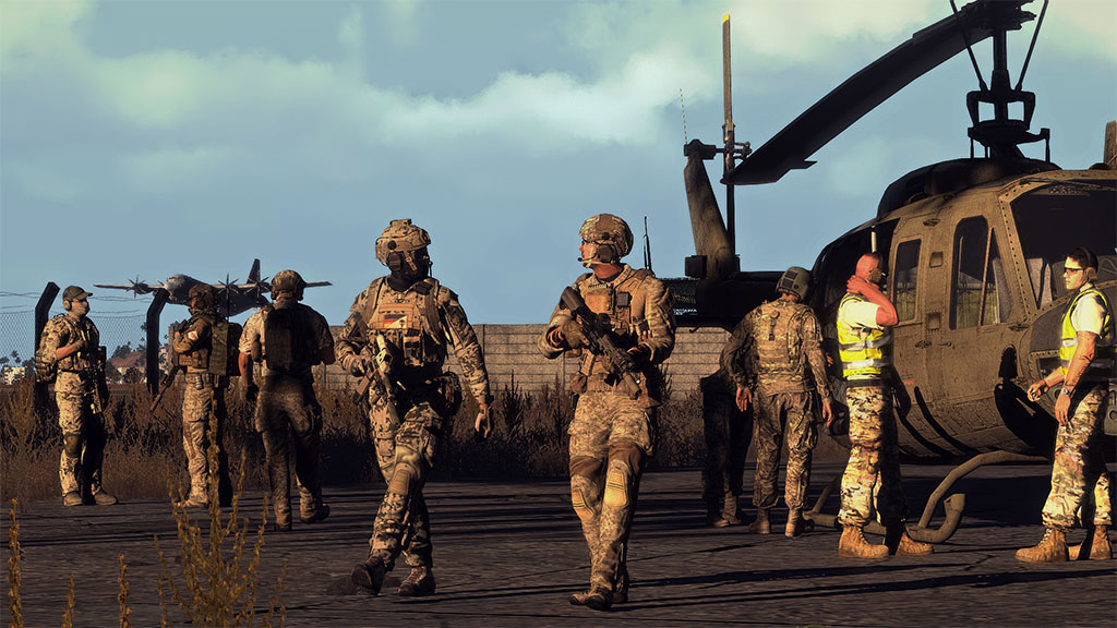 Soldiers gather around a Huey helicopter on an airfield.